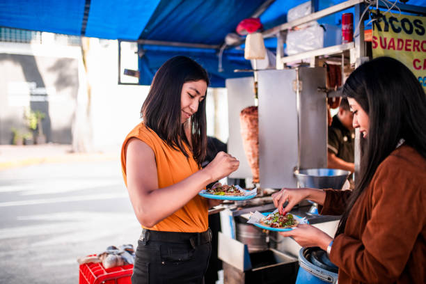 Two young women standing beside taco truck