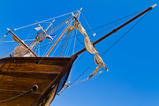 Old wooden ship with lowered sails, view from below.