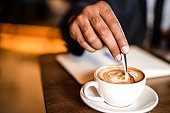 Businessman mixing coffee hand close up.
