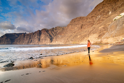 Rare View of Woman Looking at the Ocean Waves at the Beach of Playa de Los Gigantes, Canary Island Tenerife, Spain - stock photo