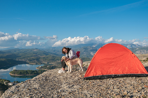 Young man and her dog camping on top of mountain