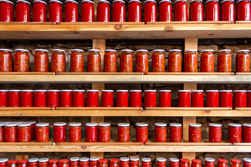Tomatoes and pepper paste in jars. Tomato paste jars lined up on shelves. Tomato and pepper sauce