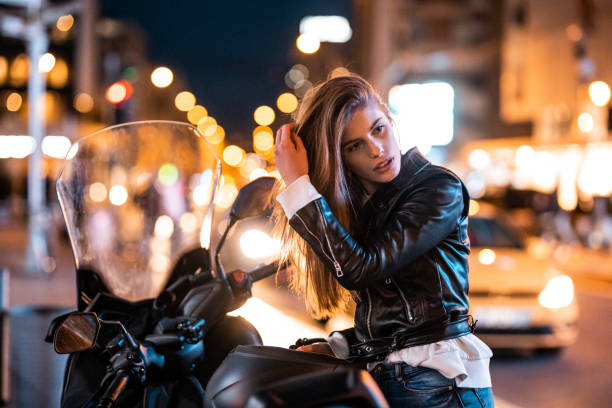 Low angle view of happy and confident young blonde woman with a jacket and backpack walking in a city street and blue sky in background