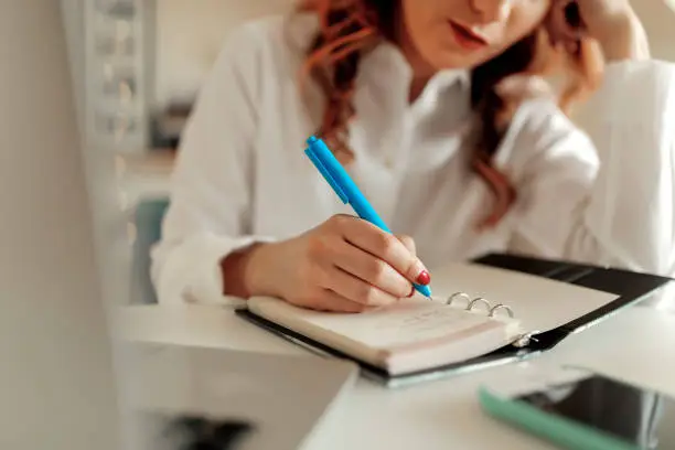 Cropped shot of a businesswoman making notes at her desk in a modern office