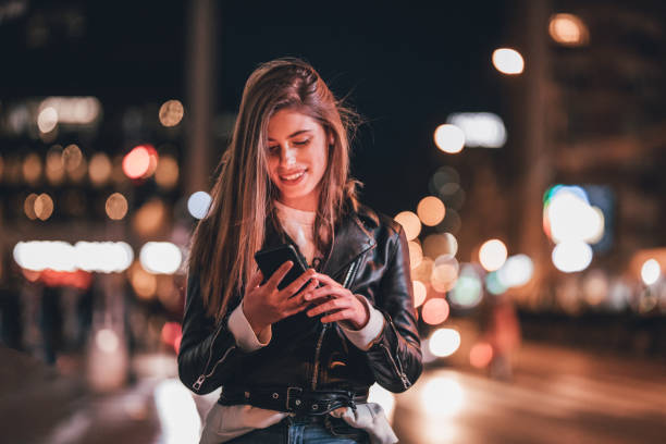 istock Young woman standing on sidewalk and using phone 1192169044