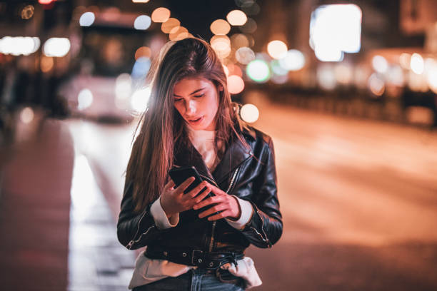 istock Young woman standing on sidewalk and using phone 1192169128