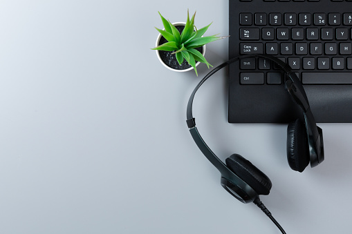 Keyboard a plants and earphones on a gray background with microphone with copy space