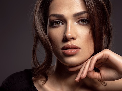 Beautiful woman with brown hair. Attractive model with brown eyes. Fashion model with a smokey makeup. Closeup portrait of a pretty woman looks at camera.