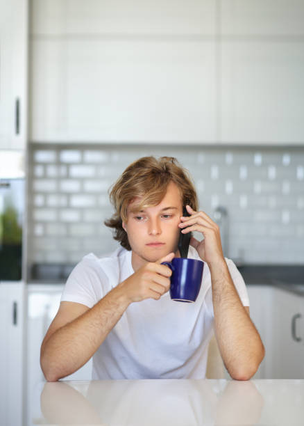 istock Teenage boy typing text message.Sitting in the kitchen.Using smart phone 1192170862