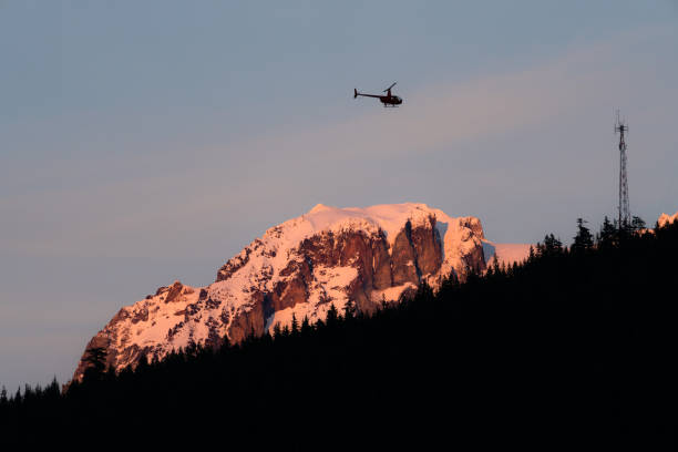 istock Helicopter flying over mountain in red light during sunset 1192177011