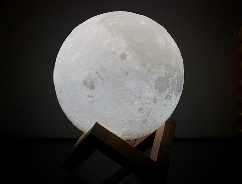 Moon lamp bright night light with astonishing design laying on top of a symmetric shape.