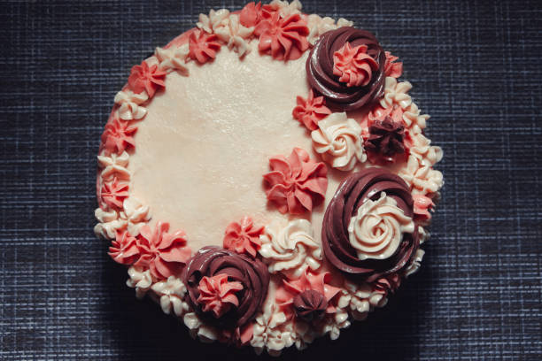 istock Pink cake with cream flowers on a dark background 1192192024