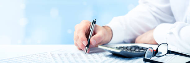 Business Man Using Pen And Calculator On Desk stock photo