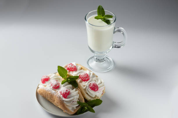 Kefir is decorated with a leaf of mint, a fermented drink. Air cake on a saucer on a white background stock photo