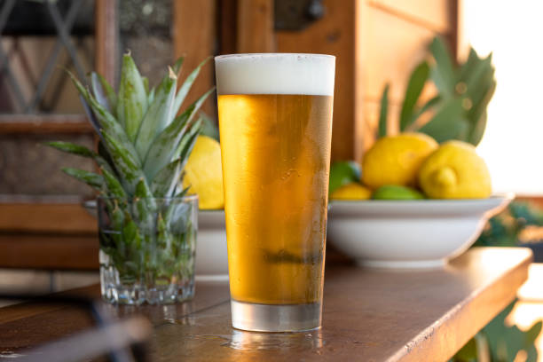 Beer In A Cold Glass On A Timber Bar Counter With A Summer FeelAnd Fruit In The Background