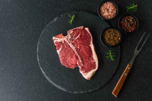 rohes t-bone porterhouse rindfleisch steak fleisch mit chimichurri sauce vor schwarzem stein hintergrund - chimichurri horizontal beef steak stock-fotos und bilder