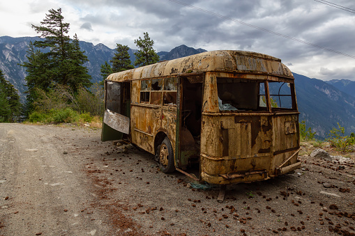 Old, Rusty, Broken and Abandoned Bus on a Dirt Road in the Mountain Valley near a lake during a cloudy summer evening. Taken on Anderson Lake Rd, near Lillooet, BC, Canada.