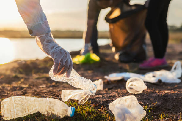 istock people volunteer keeping garbage plastic bottle into black bag at park river in sunset 1192215251