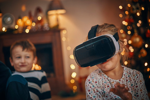 Little Kids Playing with a VR Googles in Living Room in a Cosy Christmas Atmosphere