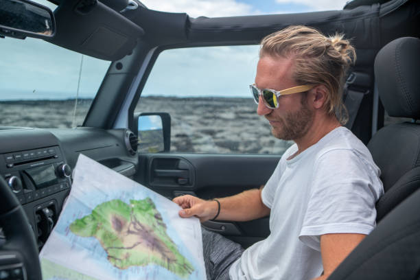 istock Young man inside 4x4 car looking at road map for directions 1192220664