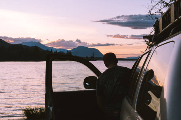 istock Man entering vehicle next to lake during sunset 1192223665