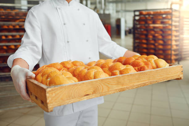 Baker's hands hold a tray with fresh bread at the bakery. Bakery concept.