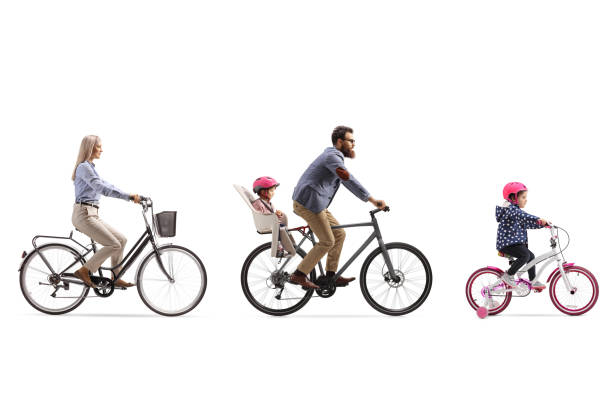 active family of a mother, father with child in a seat and a little girl riding bicycles - helmet bicycle little girls child imagens e fotografias de stock