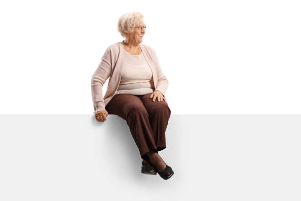 istock Elderly woman sitting on a blank panel and looking to the side 1192231443