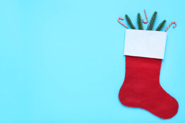 istock Red christmas stocking with fir tree branches and candy canes on blue background 1192232213