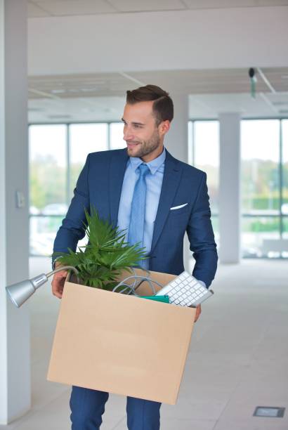 istock Young attractive businessman carrying box while relocating to his new office 1192232685