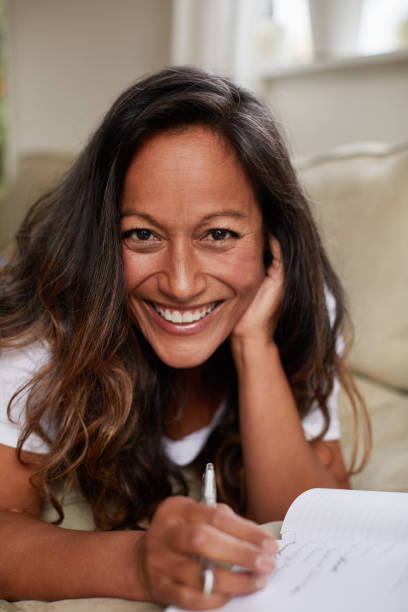 istock Smiling mature woman lying on her sofa writing in a journal 1192246172