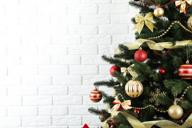 istock Christmas fir tree with ornaments on white brick wall background 1192251498