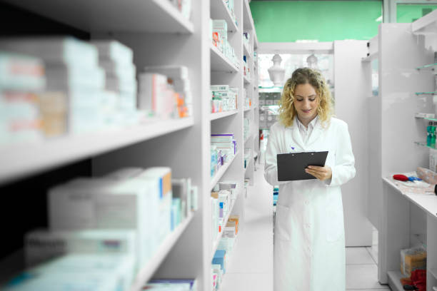 istock Pharmacist in white uniform walking by the shelf with medicines and checking inventory. Pharmaceutical industry. 1192252600