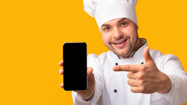 istock Chef Man Pointing Finger At Smartphone Screen, Yellow Background, Panorama 1192254122