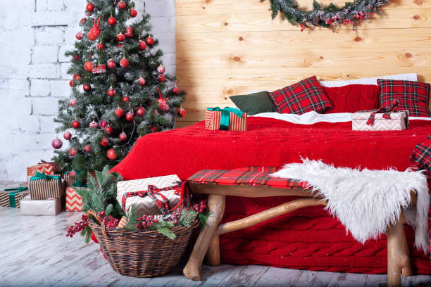 Rustic bedroom interior for christmas. Scandinavian New Year interior with pillows. Textural light room of rural house with Christmas tree. Wood and nature concept in room interior style. Hygge decor