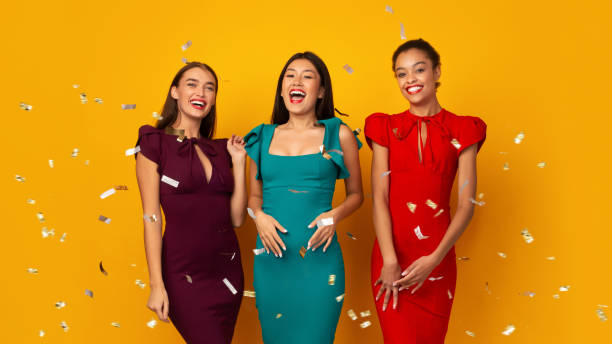 istock Excited Diverse Women Standing Under Falling Confetti, Yellow Background, Panorama 1192255785