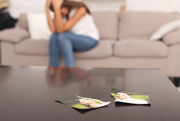 Woman Crying After Breakup With Ex-Boyfriend Sitting On Sofa Indoor Unrecognizable Woman Crying After Breakup With Ex Boyfriend Sitting On Sofa Indoor, Torn Apart Photo Of Couple Lying On Table former photos stock pictures, royalty-free photos & images