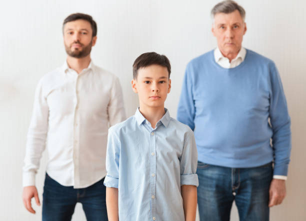 istock Boy Standing Between Father And Grandfather Next To Wall Indoor 1192256223