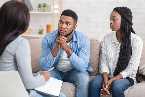 Marital Problems. Young African American Couple Listening To Counselor's Advice Sitting On Sofa During Therapy Session