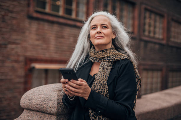 istock Modern mature lady using mobile on the street 1192258412