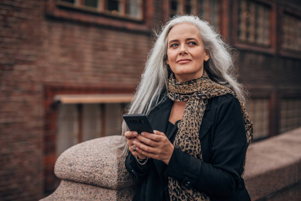istock Mature lady using mobile on the street 1192258571
