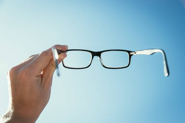 istock Hand holding glasses outdoors, blue sky, sunbeam with lens flares 1192258624