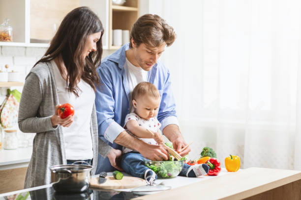 istock Cute baby boy preparing vegetable salad with parents at kitchen 1192260300