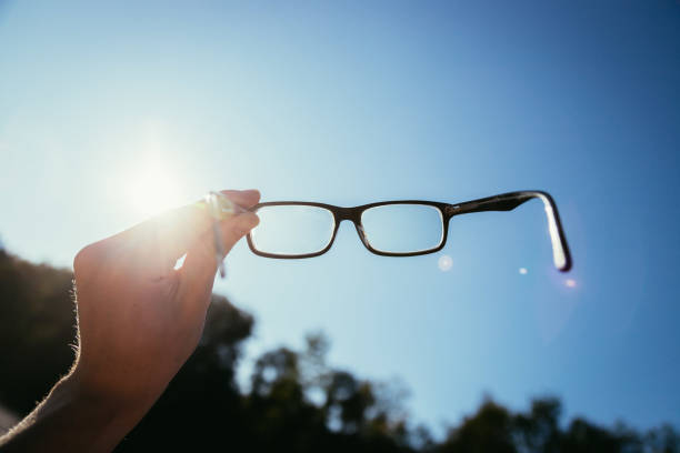 istock Hand holding glasses outdoors, blue sky, sunbeam with lens flares 1192260504