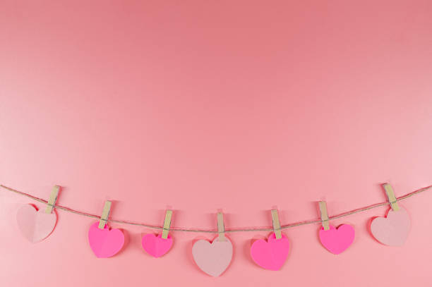 istock Paper hearts clips hanging on pink background 1192262947