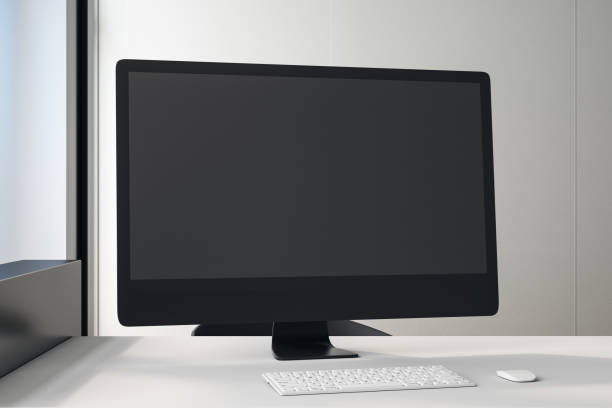 istock Black blank screen of black computer monitor on white table in light office. 1192264175