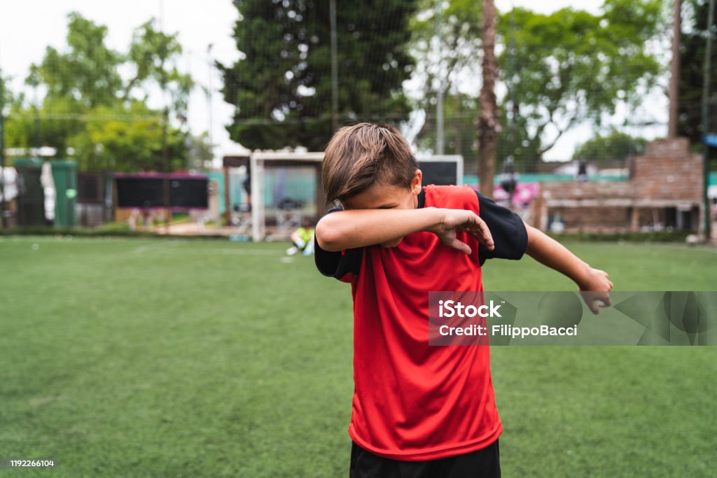 Soccer player boy doing the dab dance standing on a soccer field Soccer player boy doing the dab dance standing on a soccer field. He's celebrating. He's wearing red jersey. Soccer Stock Photo
