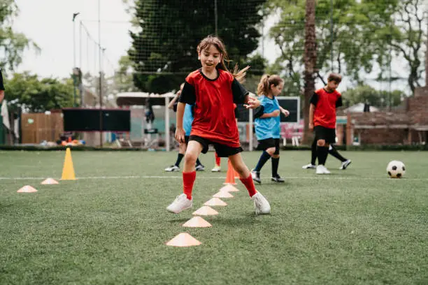 Photo of Determined girl practicing soccer drills on field