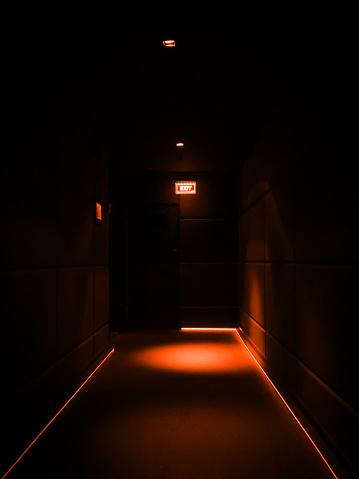 Section of an empty dark corridor illuminated with lights in a building with copy space. Lightings in warm tones.