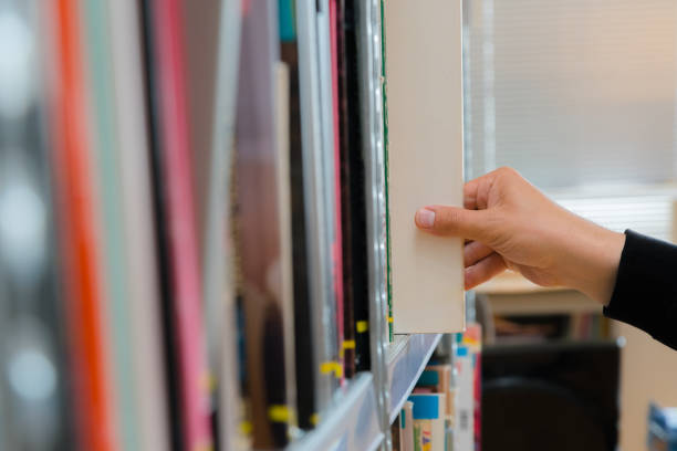 istock Young student picking a book from the shelf in the library. Preparing for exams, young man searching for or choosing a book in the public library in university 1192272047